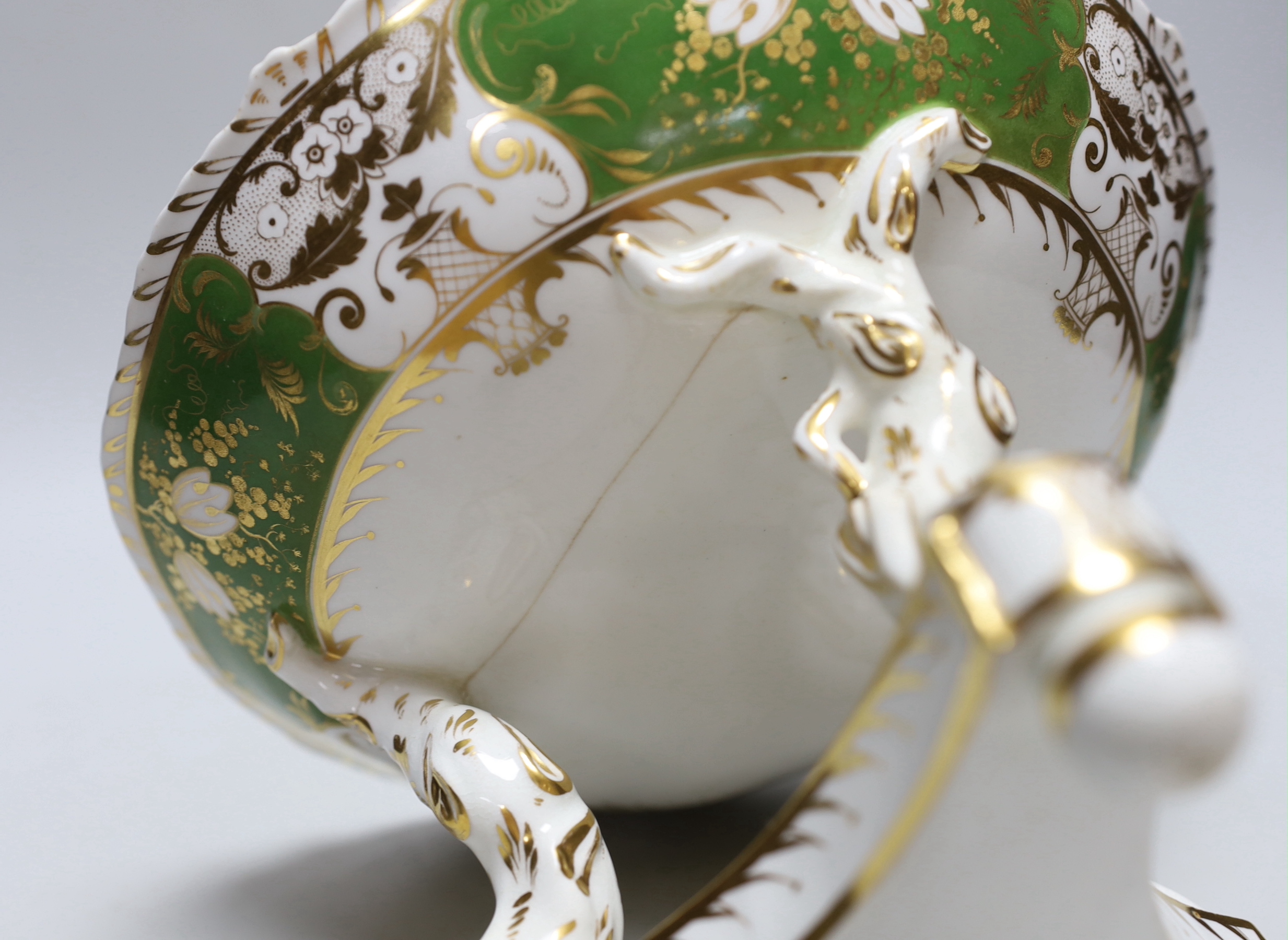 A Derby three footed comport, the centre painted with flowers, the border with green ground having four white gilded panels and four green gilded panels, c.1825, 17cm high